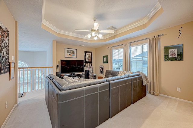 carpeted living room featuring a tray ceiling, ceiling fan, crown molding, and a textured ceiling