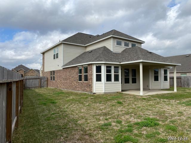 back of property with a patio area and a yard