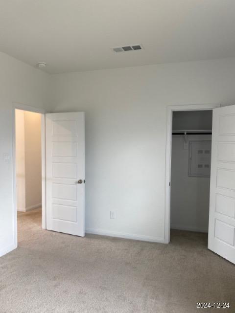 unfurnished bedroom featuring light carpet and a closet