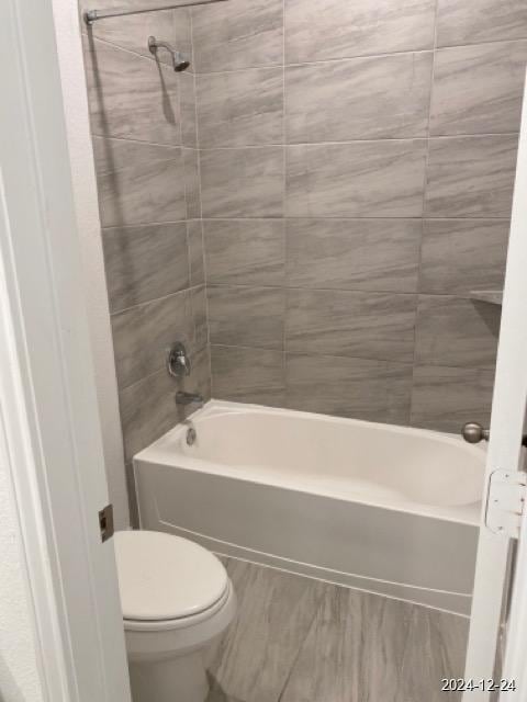 bathroom featuring toilet and tiled shower / bath