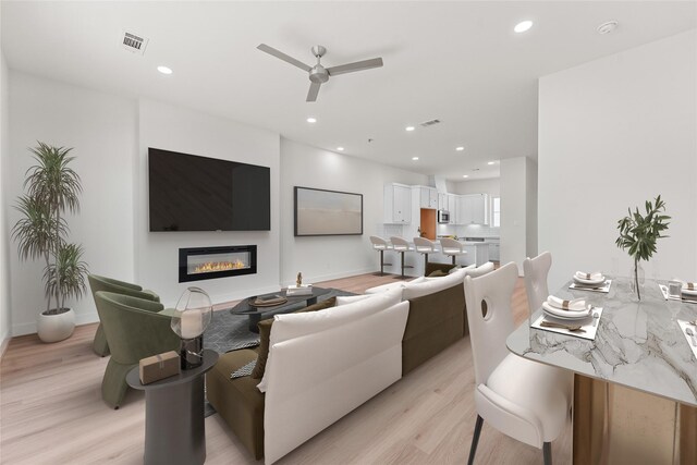 living room with ceiling fan and light hardwood / wood-style flooring