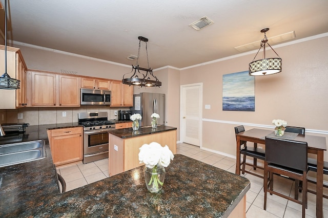 kitchen with appliances with stainless steel finishes, sink, light tile patterned floors, a center island, and hanging light fixtures