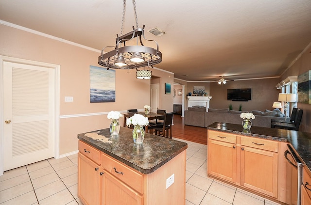 kitchen featuring ceiling fan, a center island, light tile patterned flooring, and crown molding