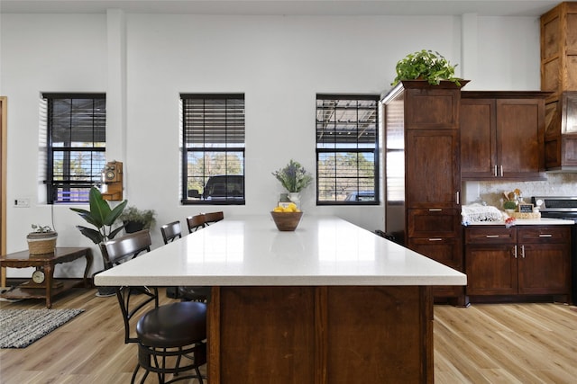 kitchen with a kitchen bar, stove, and light hardwood / wood-style flooring