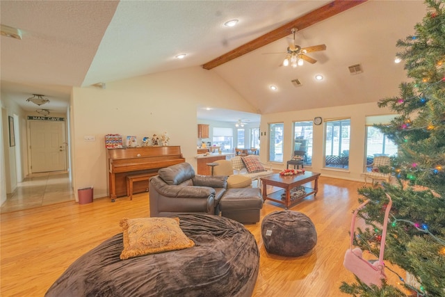 living room featuring ceiling fan, beamed ceiling, light hardwood / wood-style floors, and high vaulted ceiling