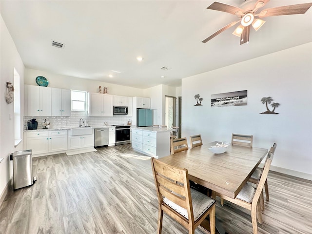 dining area with ceiling fan, sink, and light hardwood / wood-style flooring