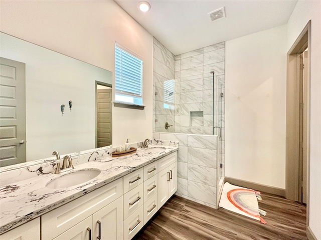 bathroom with hardwood / wood-style floors, vanity, and an enclosed shower