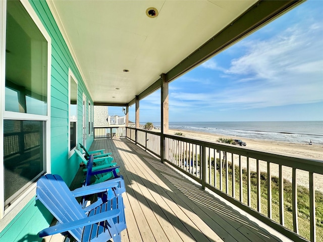 wooden deck with a water view and a view of the beach