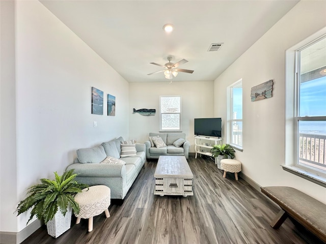 living room featuring ceiling fan, plenty of natural light, and dark wood-type flooring