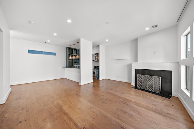 unfurnished living room featuring light hardwood / wood-style floors and a tile fireplace