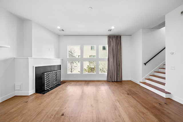 unfurnished living room featuring light hardwood / wood-style floors and a tiled fireplace