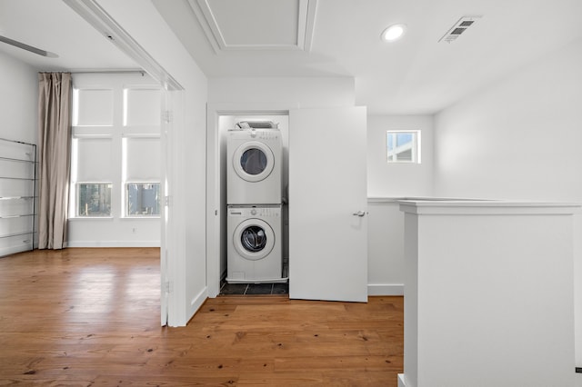 laundry area with stacked washing maching and dryer and light hardwood / wood-style floors