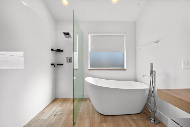 bathroom with wood-type flooring and shower with separate bathtub