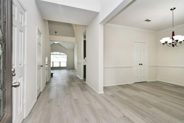 foyer entrance with ornamental molding, a chandelier, lofted ceiling, and light wood-type flooring