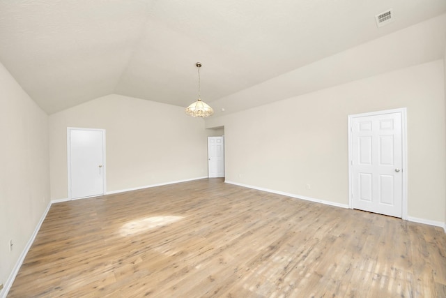 unfurnished room with light hardwood / wood-style flooring, lofted ceiling, and a notable chandelier