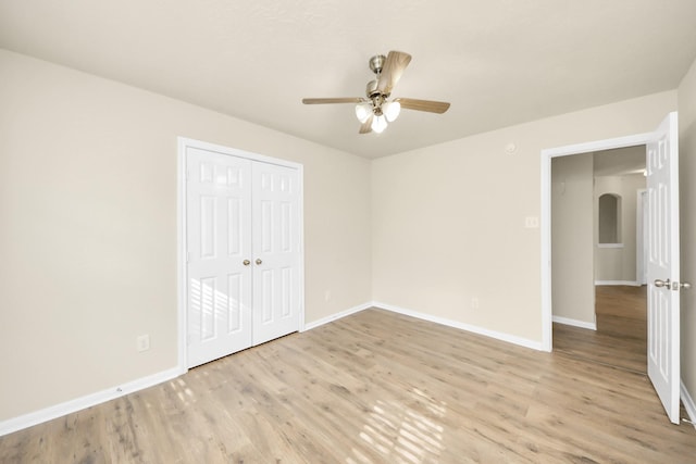 unfurnished bedroom with ceiling fan, light wood-type flooring, and a closet