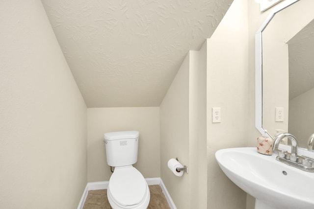 bathroom with tile patterned floors, sink, vaulted ceiling, and toilet