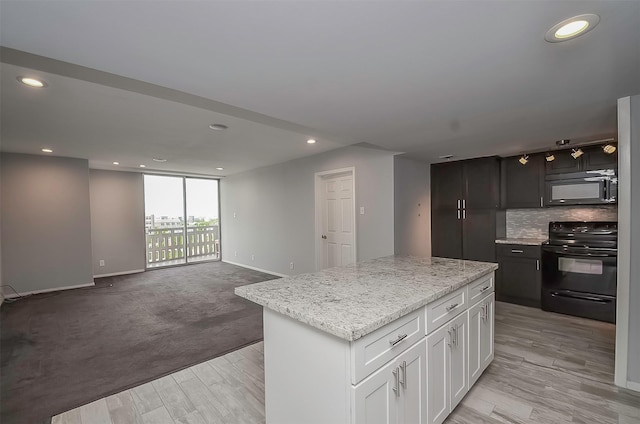 kitchen with a center island, black appliances, light wood-type flooring, light stone counters, and white cabinetry