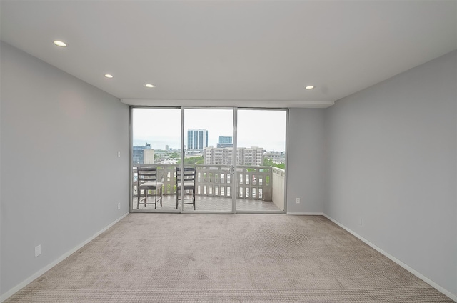 spare room featuring floor to ceiling windows and light colored carpet