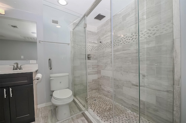 bathroom featuring vanity, toilet, and a shower with shower door