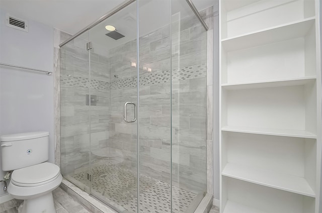 bathroom featuring toilet and a shower with door