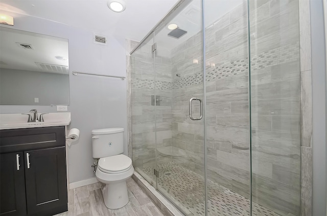 bathroom featuring vanity, toilet, and a shower with door