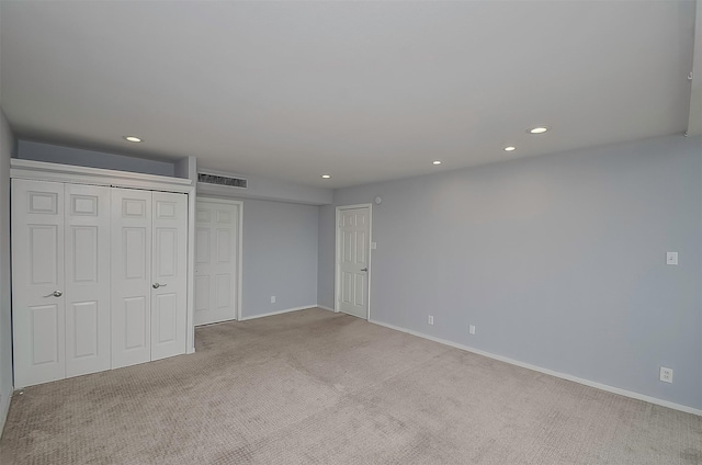 unfurnished bedroom with light colored carpet and multiple closets