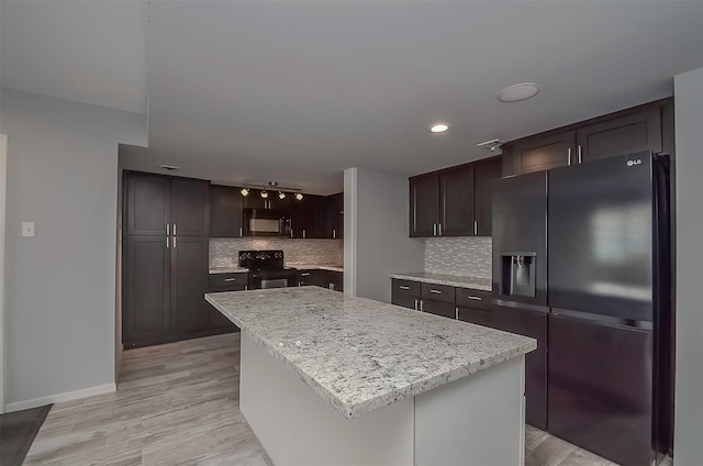 kitchen featuring decorative backsplash, light wood-type flooring, dark brown cabinetry, black appliances, and a kitchen island