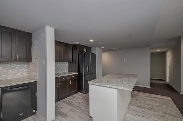 kitchen with tasteful backsplash, light stone countertops, a kitchen island, and black appliances