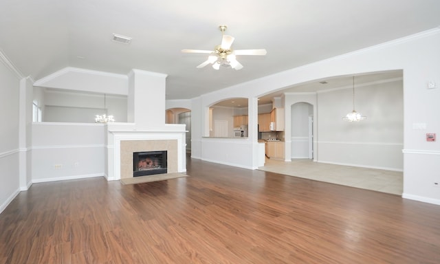 unfurnished living room with ceiling fan, crown molding, a tile fireplace, hardwood / wood-style floors, and lofted ceiling