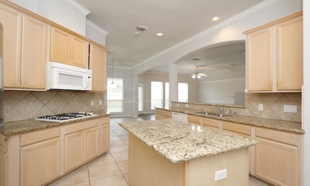 kitchen featuring ceiling fan, sink, light tile patterned floors, backsplash, and a kitchen island