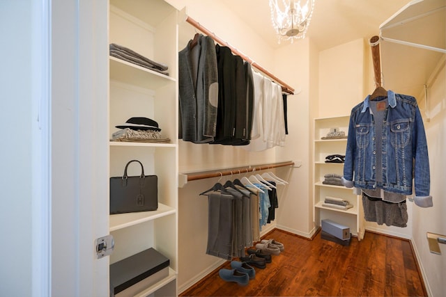 spacious closet with dark hardwood / wood-style flooring and a notable chandelier