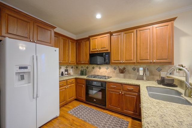 kitchen with backsplash, black appliances, sink, ornamental molding, and light hardwood / wood-style floors