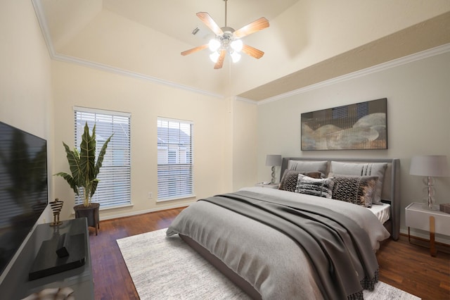 bedroom with a tray ceiling, crown molding, ceiling fan, and dark wood-type flooring