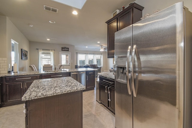 kitchen with a center island, sink, light tile patterned flooring, kitchen peninsula, and stainless steel appliances