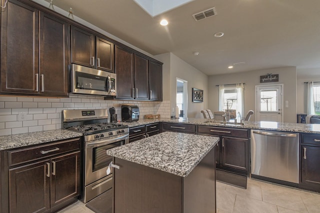 kitchen featuring sink, a center island, stainless steel appliances, backsplash, and kitchen peninsula