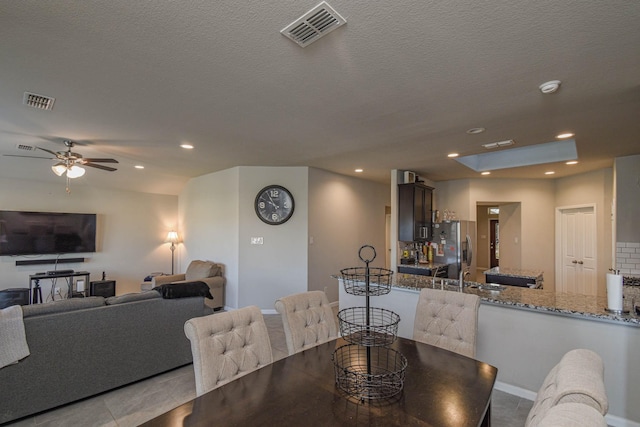 tiled dining area featuring a textured ceiling, ceiling fan, and sink