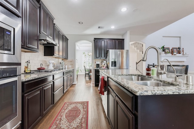 kitchen featuring a kitchen island with sink, sink, stainless steel appliances, and light hardwood / wood-style floors