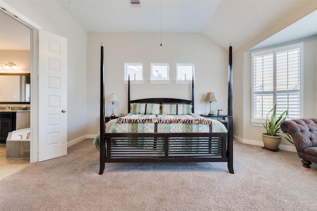 bedroom featuring ensuite bathroom, light carpet, and lofted ceiling