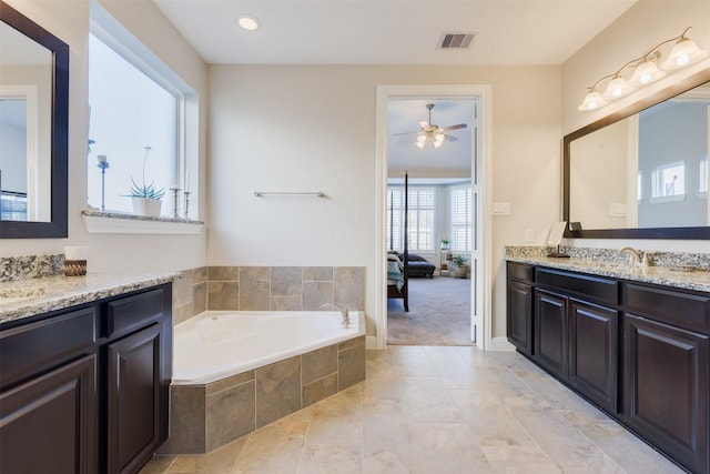 bathroom with ceiling fan, vanity, and tiled tub