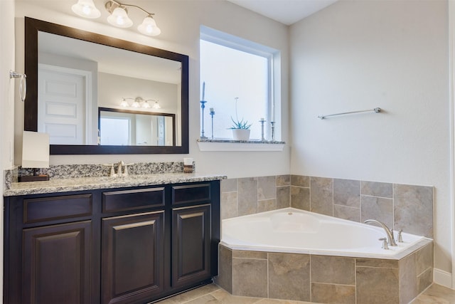 bathroom with tile patterned flooring, vanity, and tiled bath