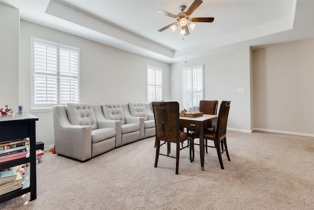 dining space featuring ceiling fan, a raised ceiling, and light colored carpet