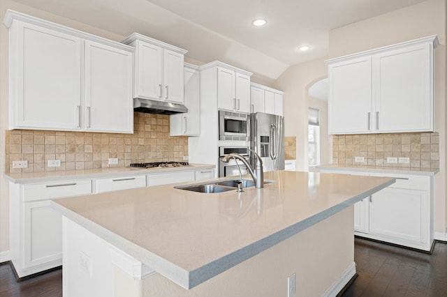 kitchen featuring decorative backsplash, appliances with stainless steel finishes, sink, white cabinetry, and an island with sink