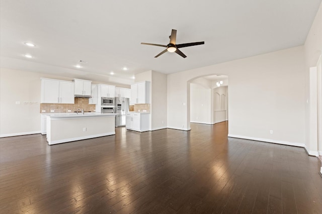 unfurnished living room with ceiling fan, sink, and dark wood-type flooring