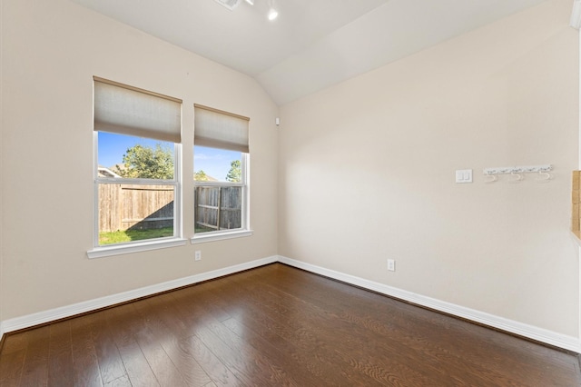 empty room with dark wood-type flooring and lofted ceiling