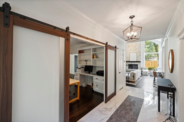 office area featuring a fireplace, a barn door, an inviting chandelier, and ornamental molding