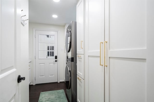 laundry room featuring dark hardwood / wood-style flooring and stacked washer and clothes dryer