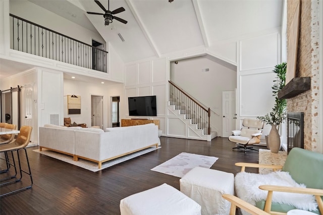 living room featuring ceiling fan, beam ceiling, high vaulted ceiling, a fireplace, and dark hardwood / wood-style floors