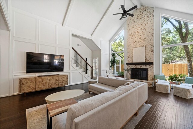 living room featuring beam ceiling, dark hardwood / wood-style flooring, a large fireplace, and high vaulted ceiling