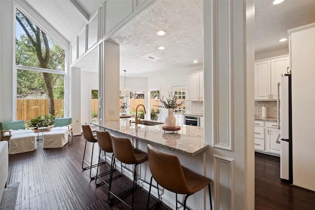 kitchen featuring white cabinets, decorative backsplash, a kitchen bar, and sink